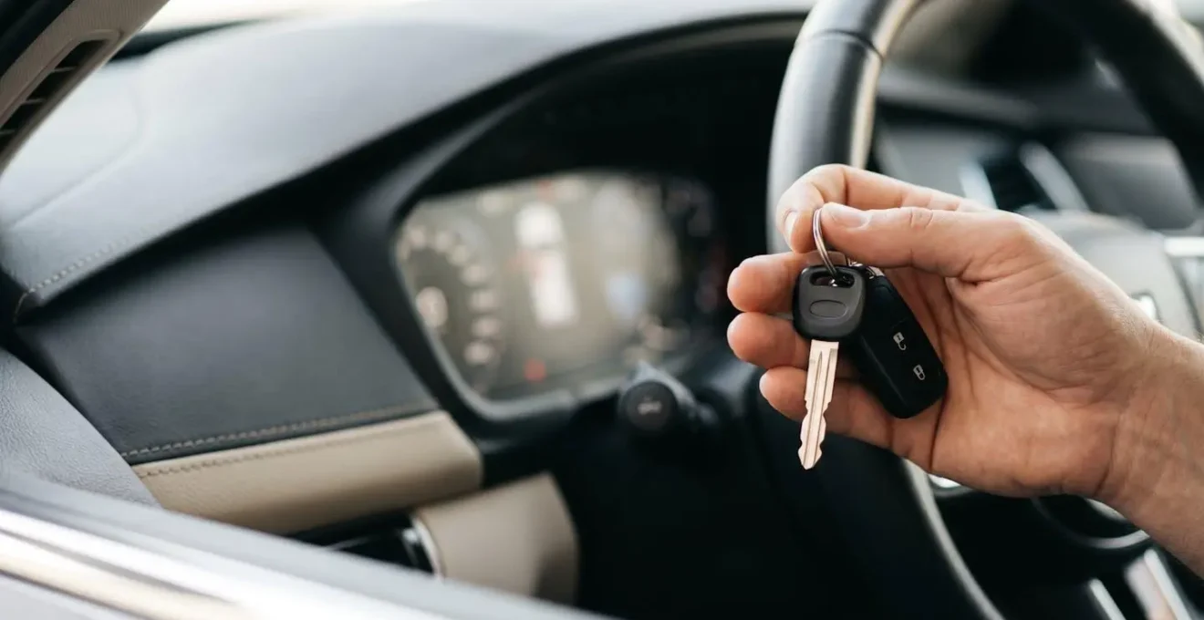 Vue rapprochée d'une main tenant des clés de voiture devant un tableau de bord moderne, symbolisant le choix d'assurance pour un véhicule