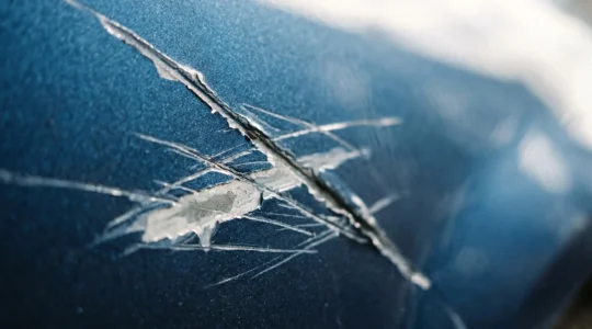 Détail d'une carrosserie automobile vandalisée avec des traces de dégradation intentionnelle
